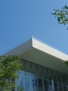 A modern sustainable building surrounded by greenery under a clear blue sky.