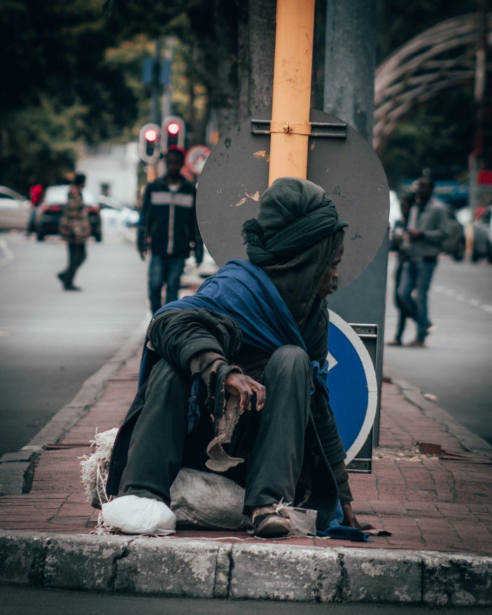 woman in black hijab sitting on sidewalk during daytime