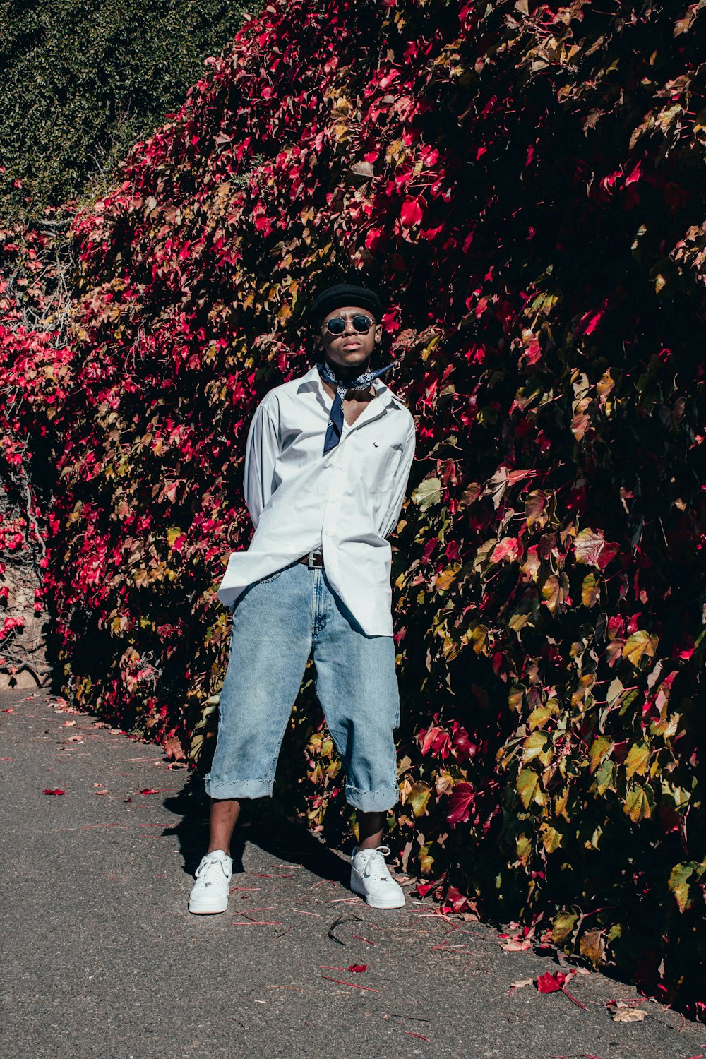 woman in white dress shirt and blue denim jeans standing on red leaves