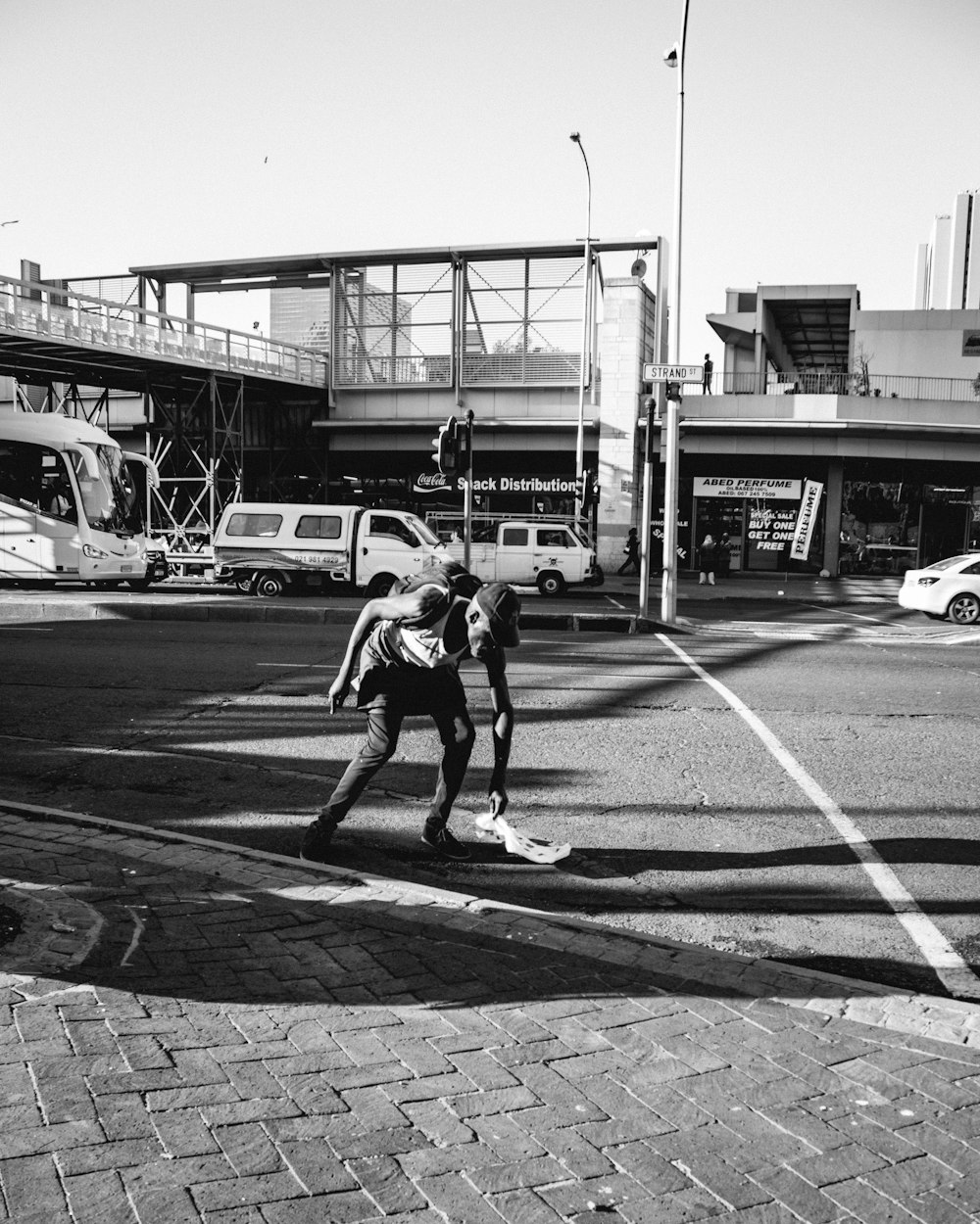 grayscale photo of man in black t-shirt and shorts walking on pedestrian lane