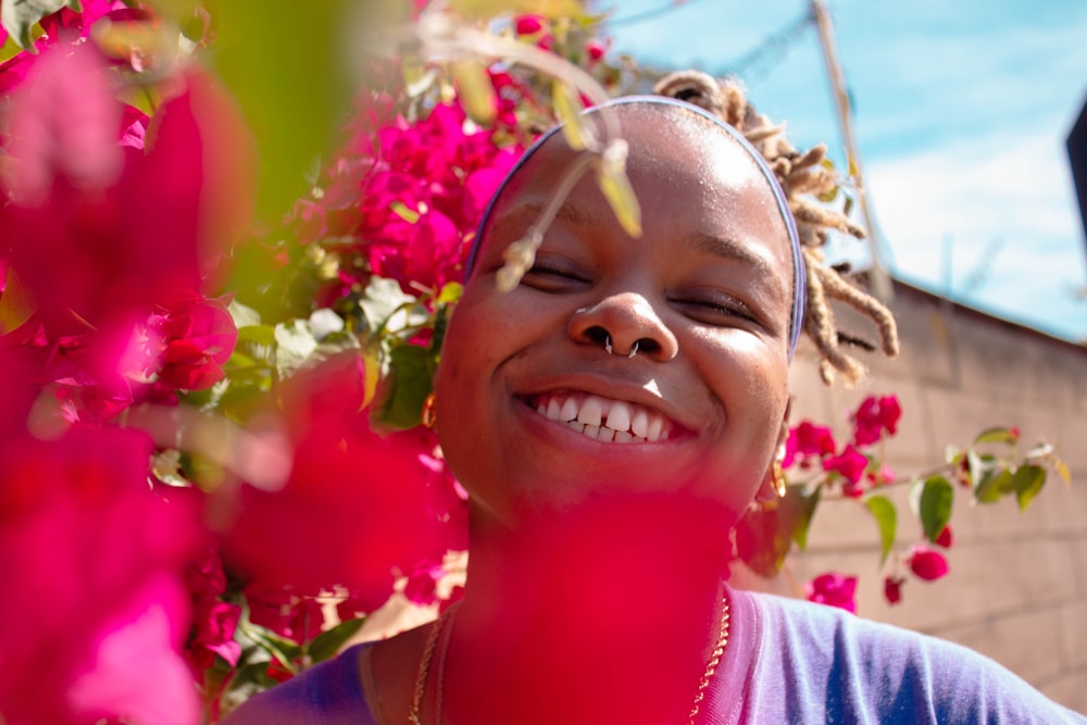 Chica sonriente en camisa rosa con corona de flores rosas