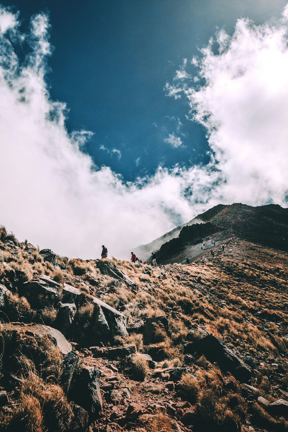 person standing on rocky mountain under blue sky during daytime