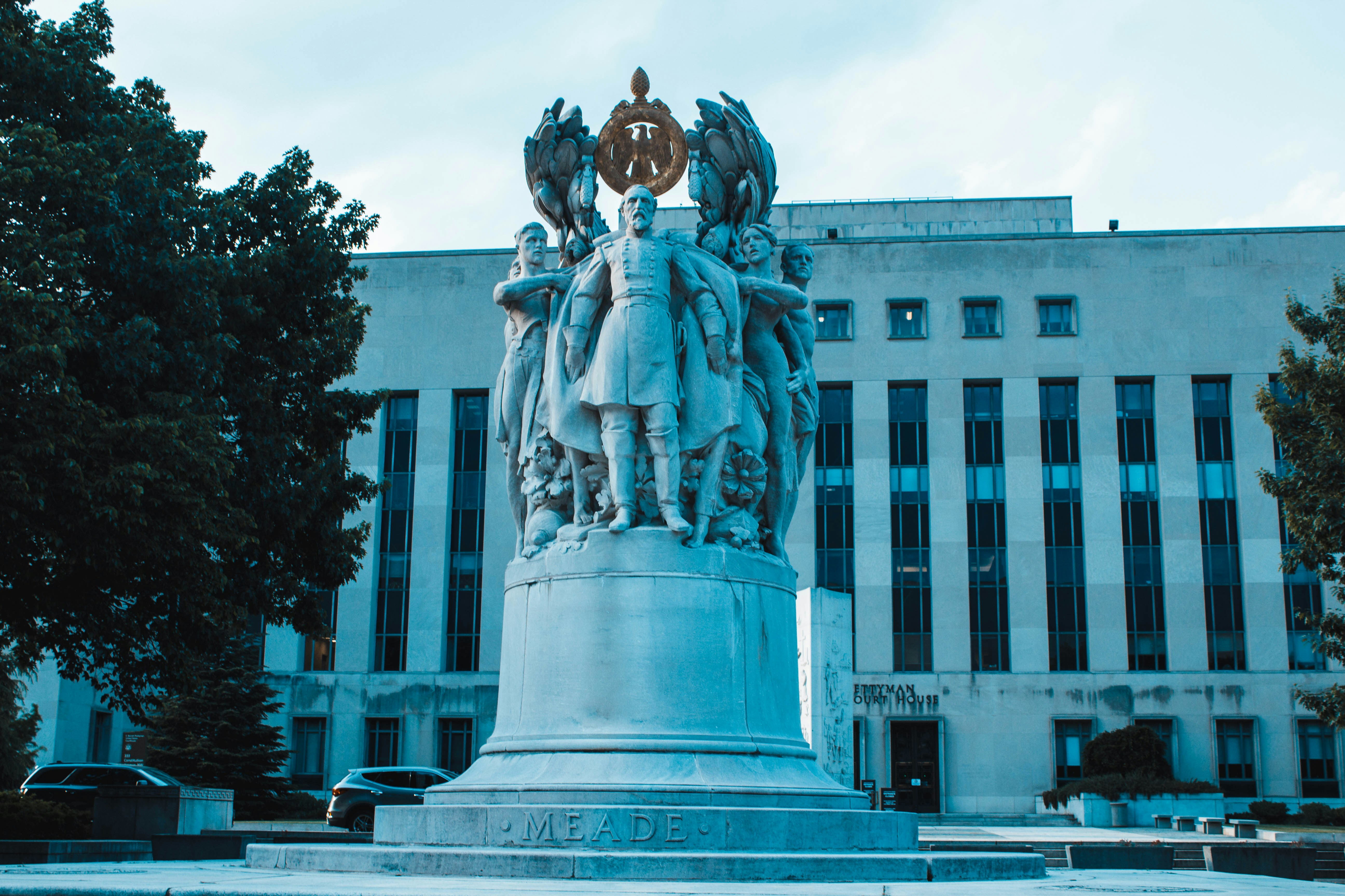 gray concrete statue near white concrete building during daytime