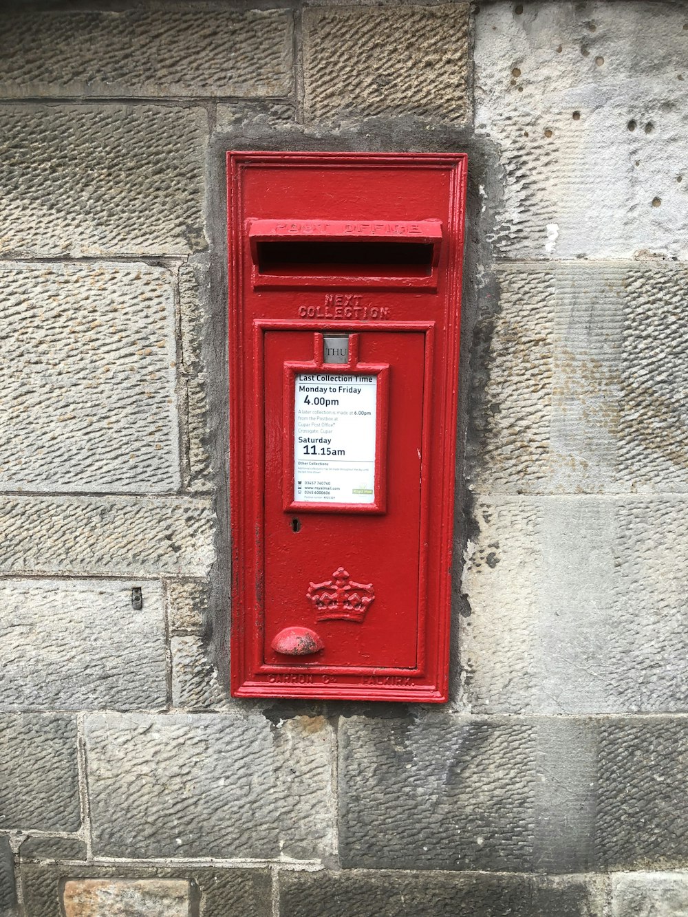 red and black mail box mounted on gray concrete wall