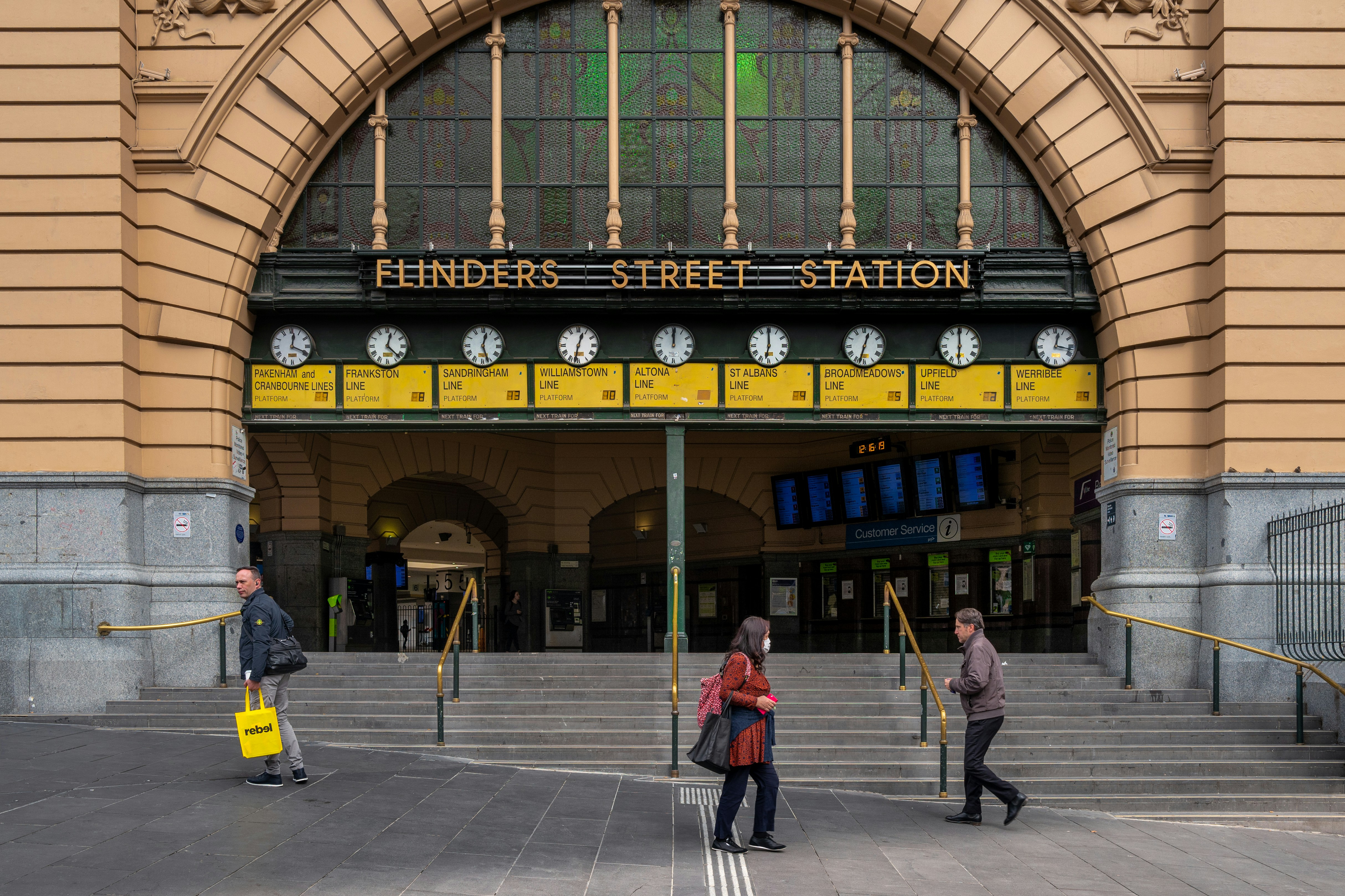 man in red jacket standing near blue and yellow UNKs building