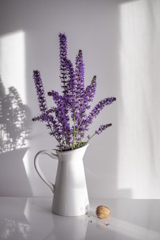 purple flowers in white ceramic vase