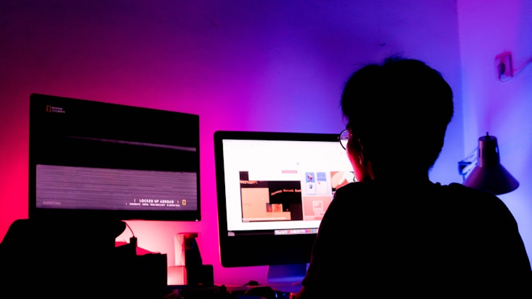 A futuristic workspace with glowing screens and a person analyzing data.