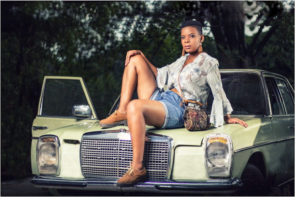 woman in blue denim jacket sitting on white car