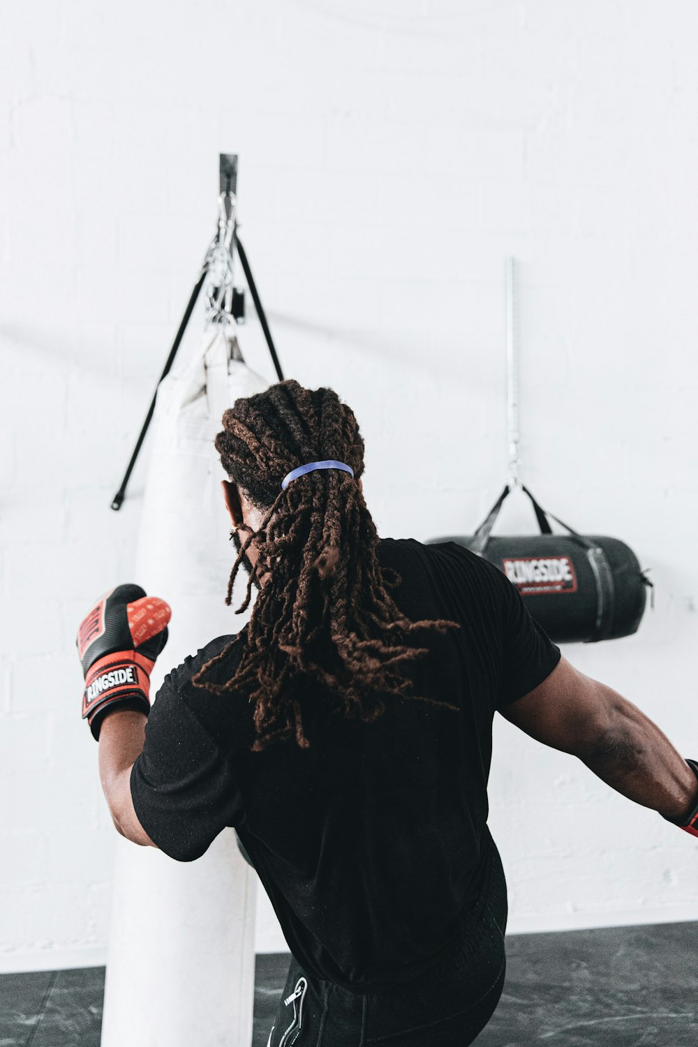 homem na camiseta preta do pescoço da tripulação vestindo luvas de boxe vermelhas e pretas