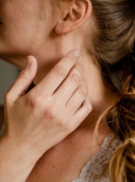 Close-up of a singer gently touching their throat, reflecting concern and care.
