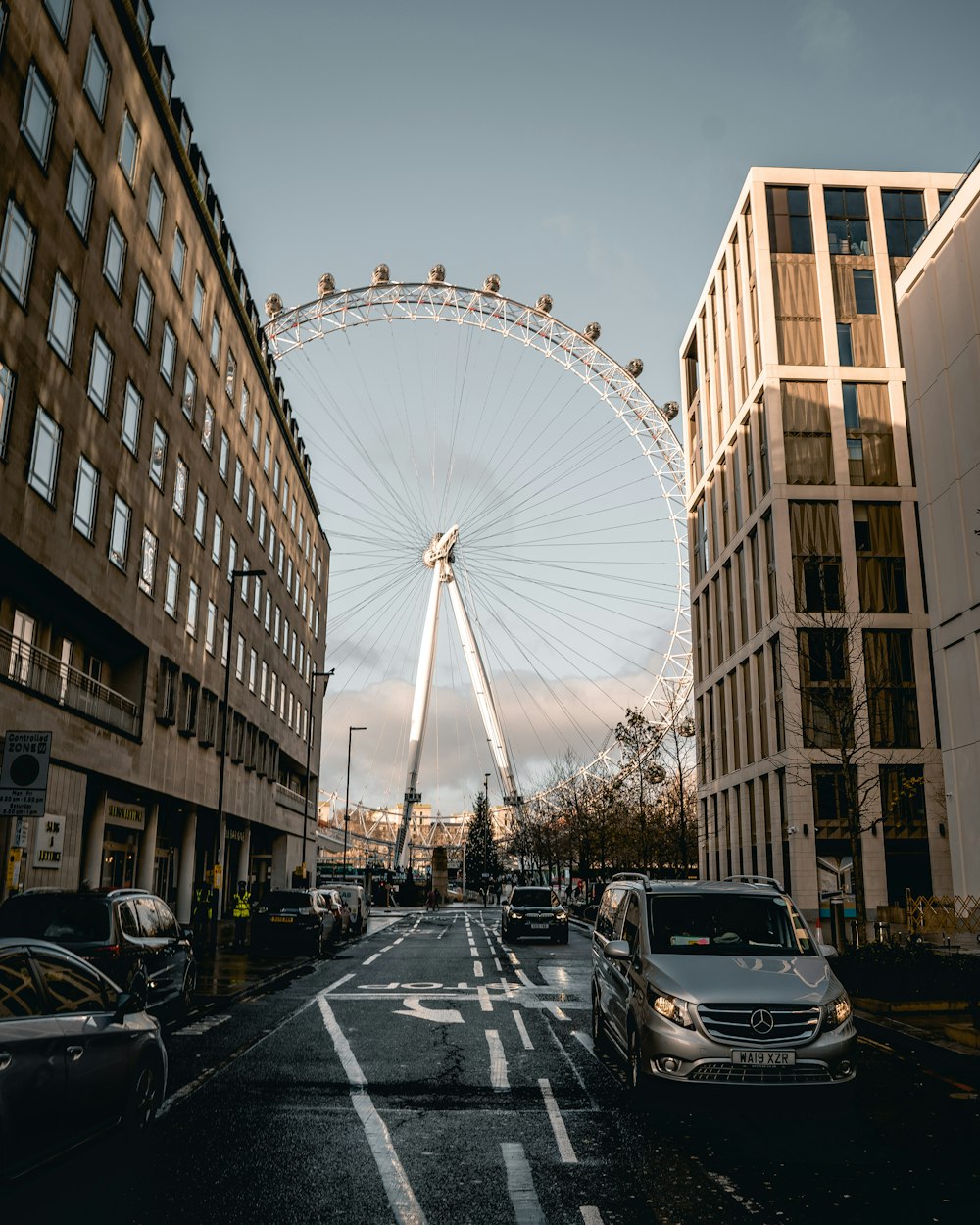 cars parked on side of road near ferris wheel during daytime