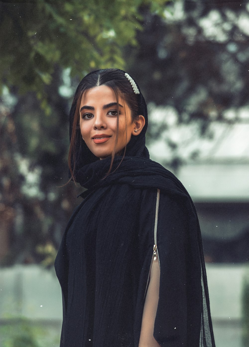 woman in black hoodie standing near green trees during daytime