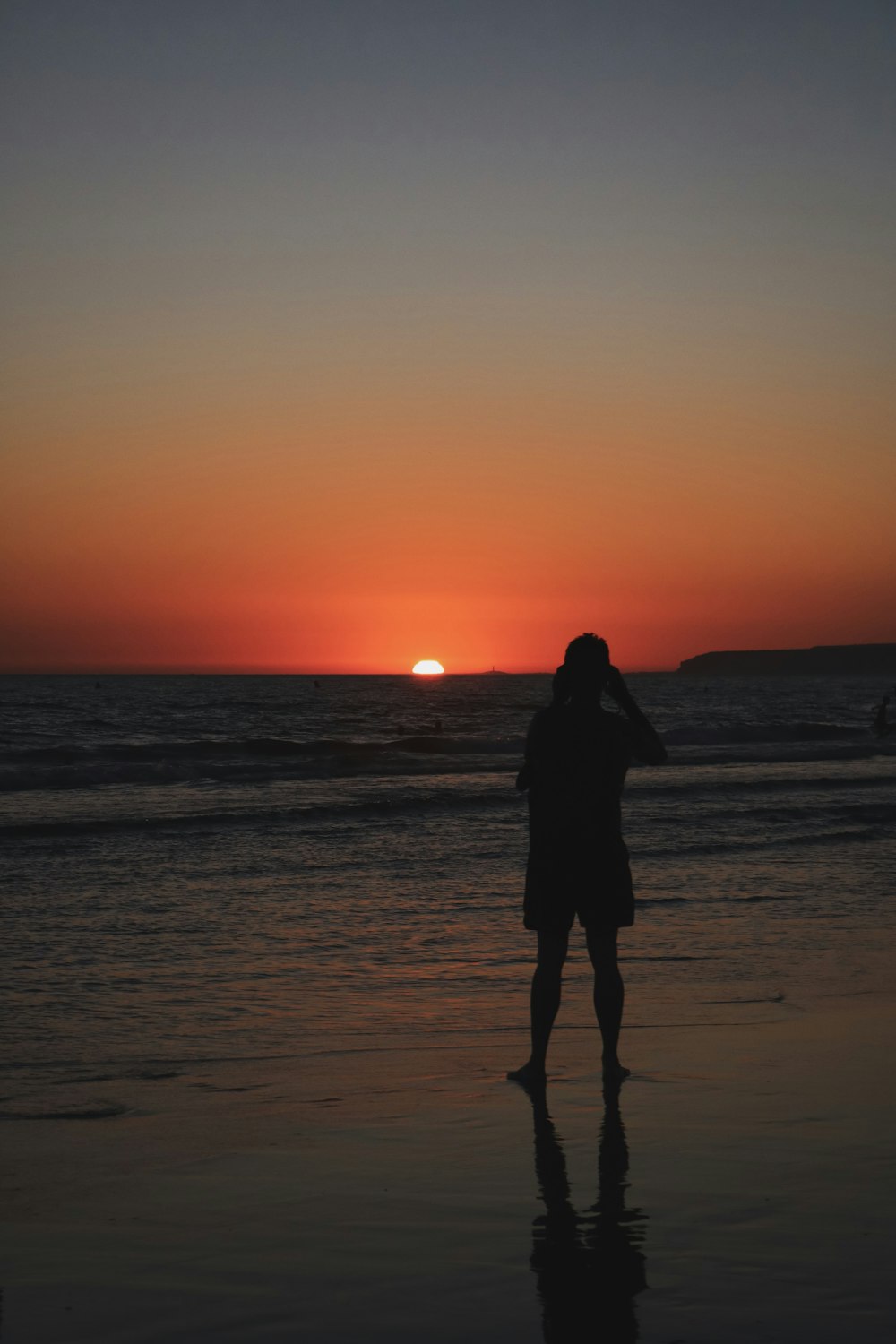 silhouette of woman standing on beach during sunset