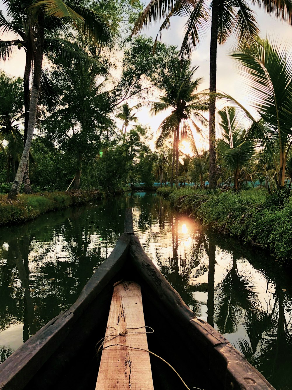 brown wooden boat on lake during sunset