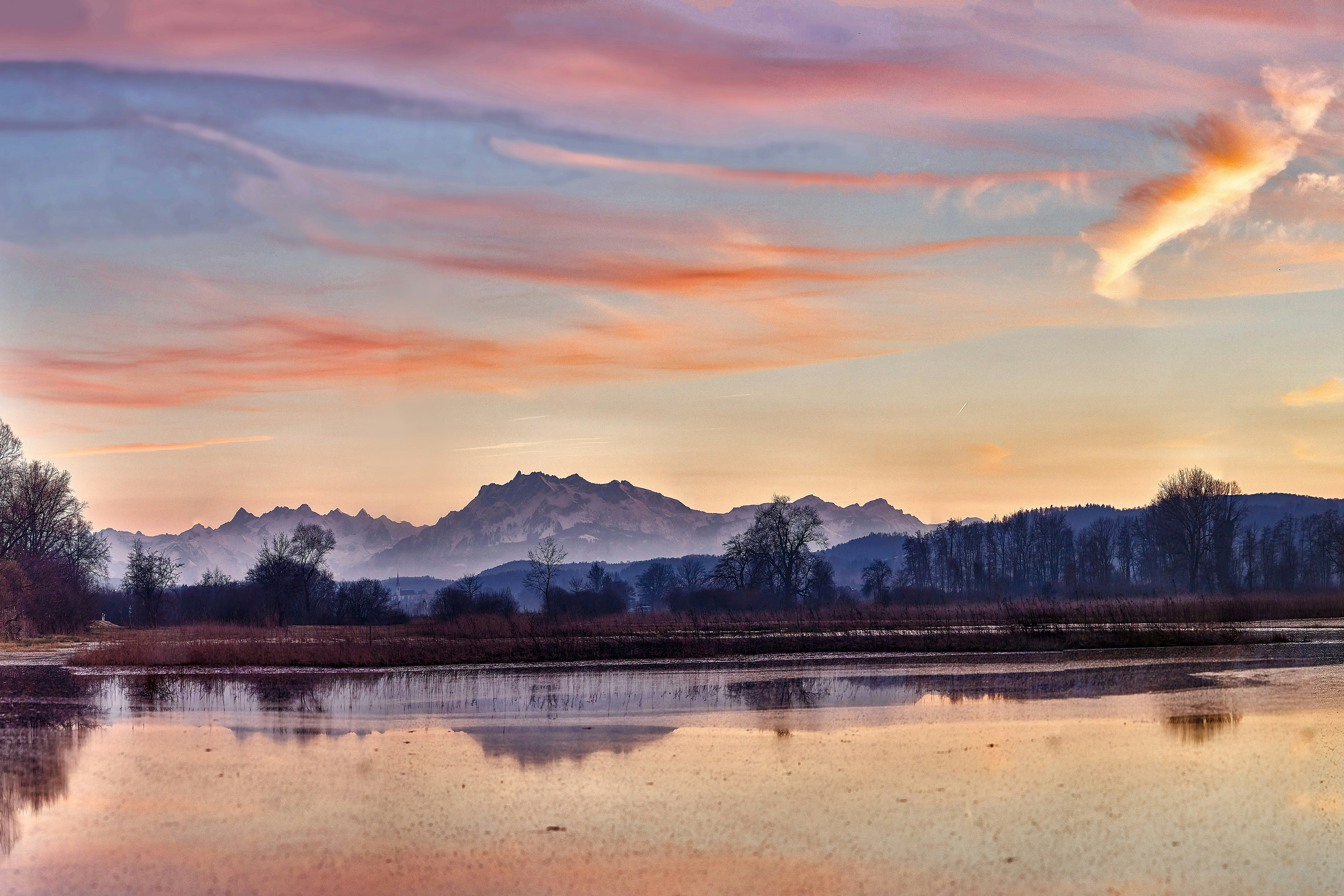 body of water near mountain during sunset
