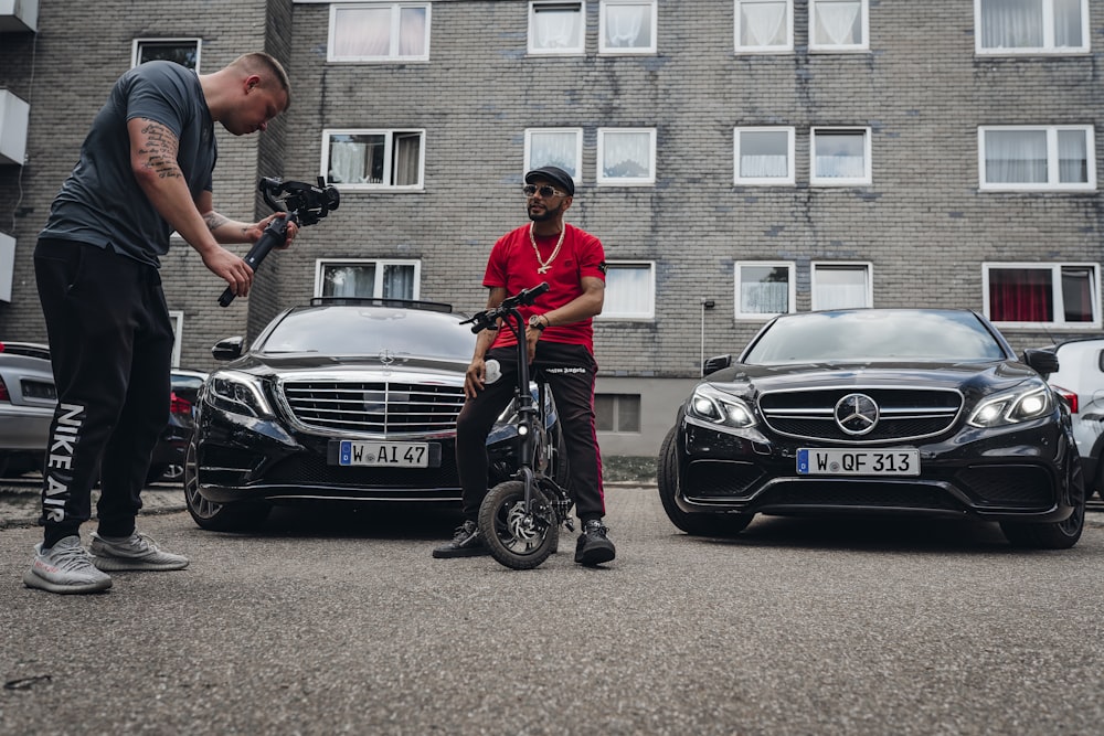 Uomo in polo rossa e pantaloni neri che cavalca l'auto nera di Mercedes Benz
