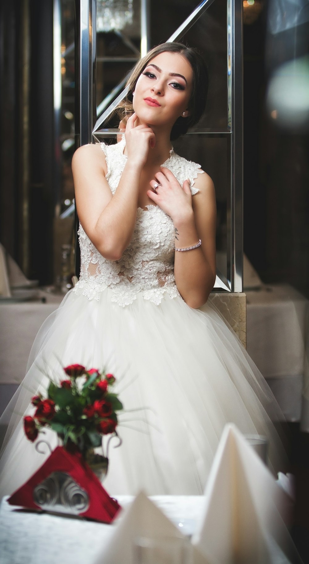 woman in white wedding dress holding bouquet of red roses