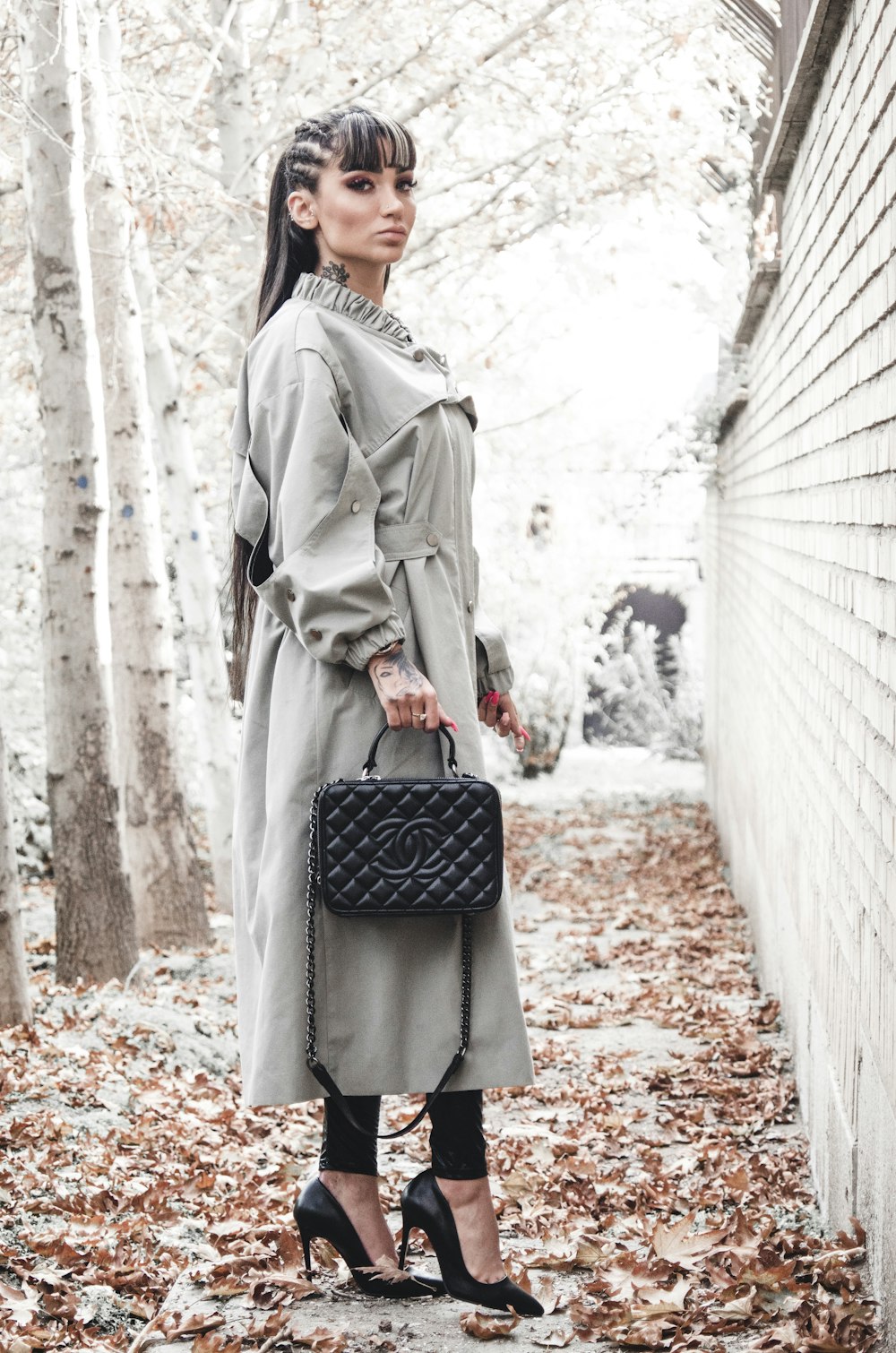 woman in gray coat holding black leather handbag