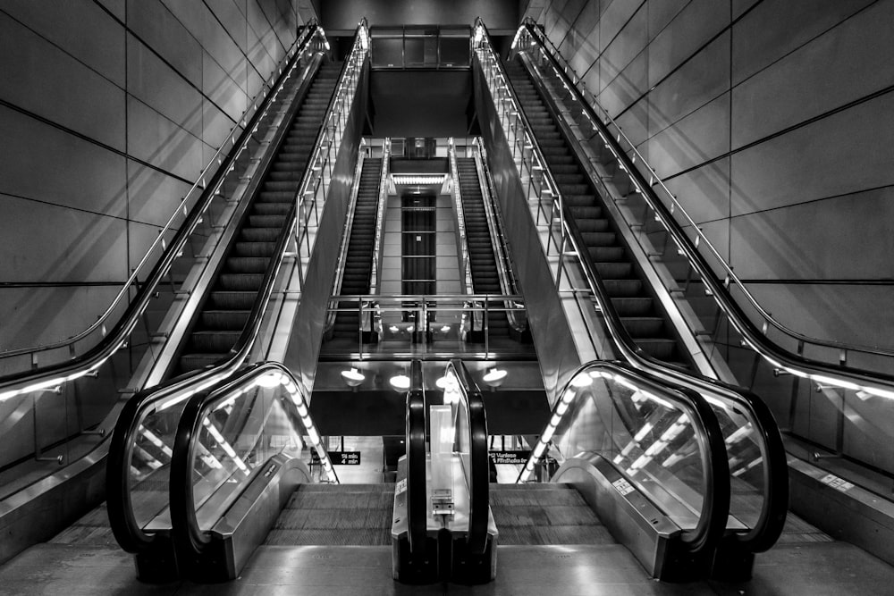 grayscale photo of escalator inside building