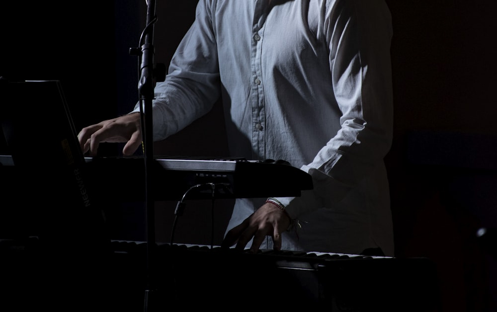 man in white dress shirt standing in front of microphone