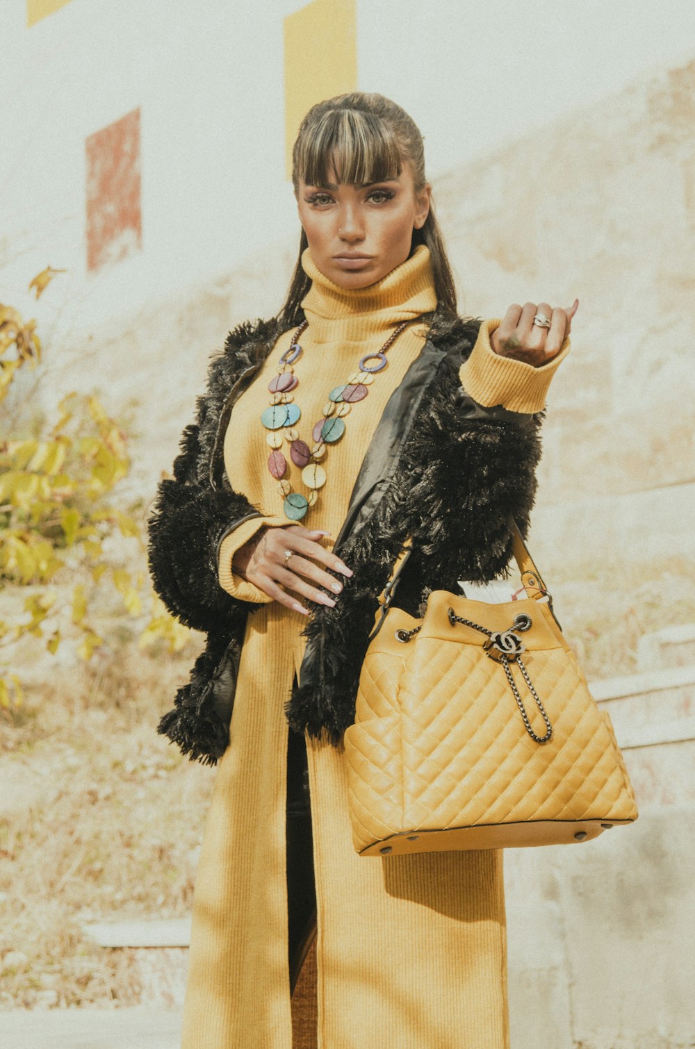 woman in yellow coat holding black fur scarf