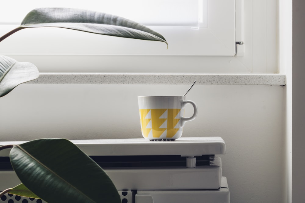 white and yellow ceramic mug on white plastic drawer