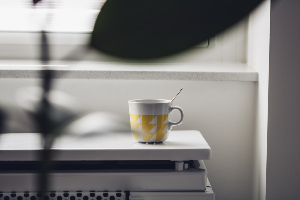 yellow and white ceramic mug on white and black table