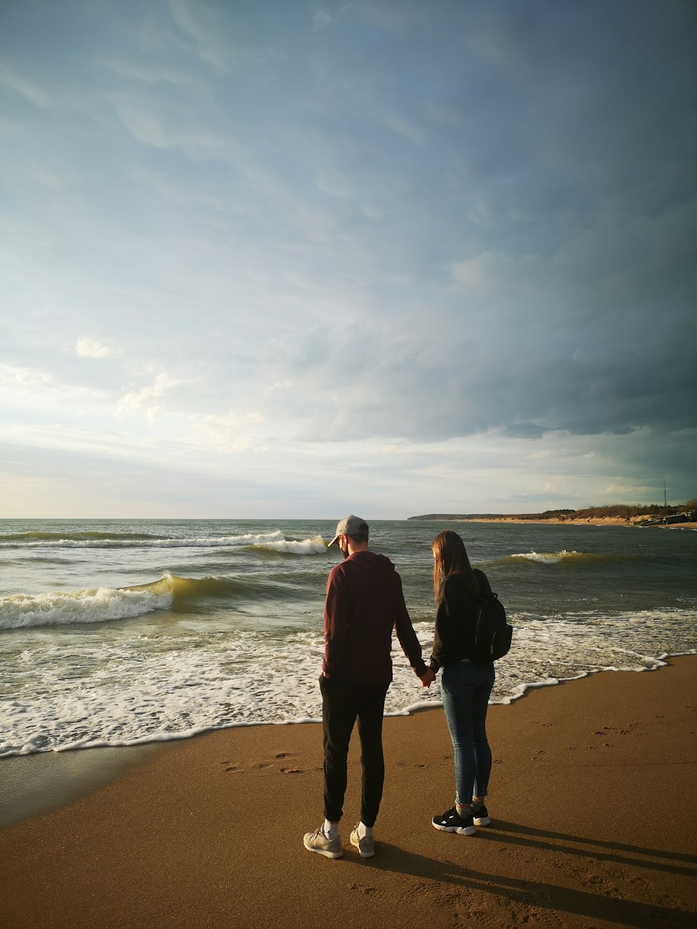 couple walking on beach during daytime