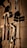 Various tools including a hammer, wrenches, and cables hang on a vertically striped surface. The light casts strong shadows, creating a dramatic effect with the tools silhouetted against the background.