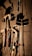 Various tools including a hammer, wrenches, and cables hang on a vertically striped surface. The light casts strong shadows, creating a dramatic effect with the tools silhouetted against the background.