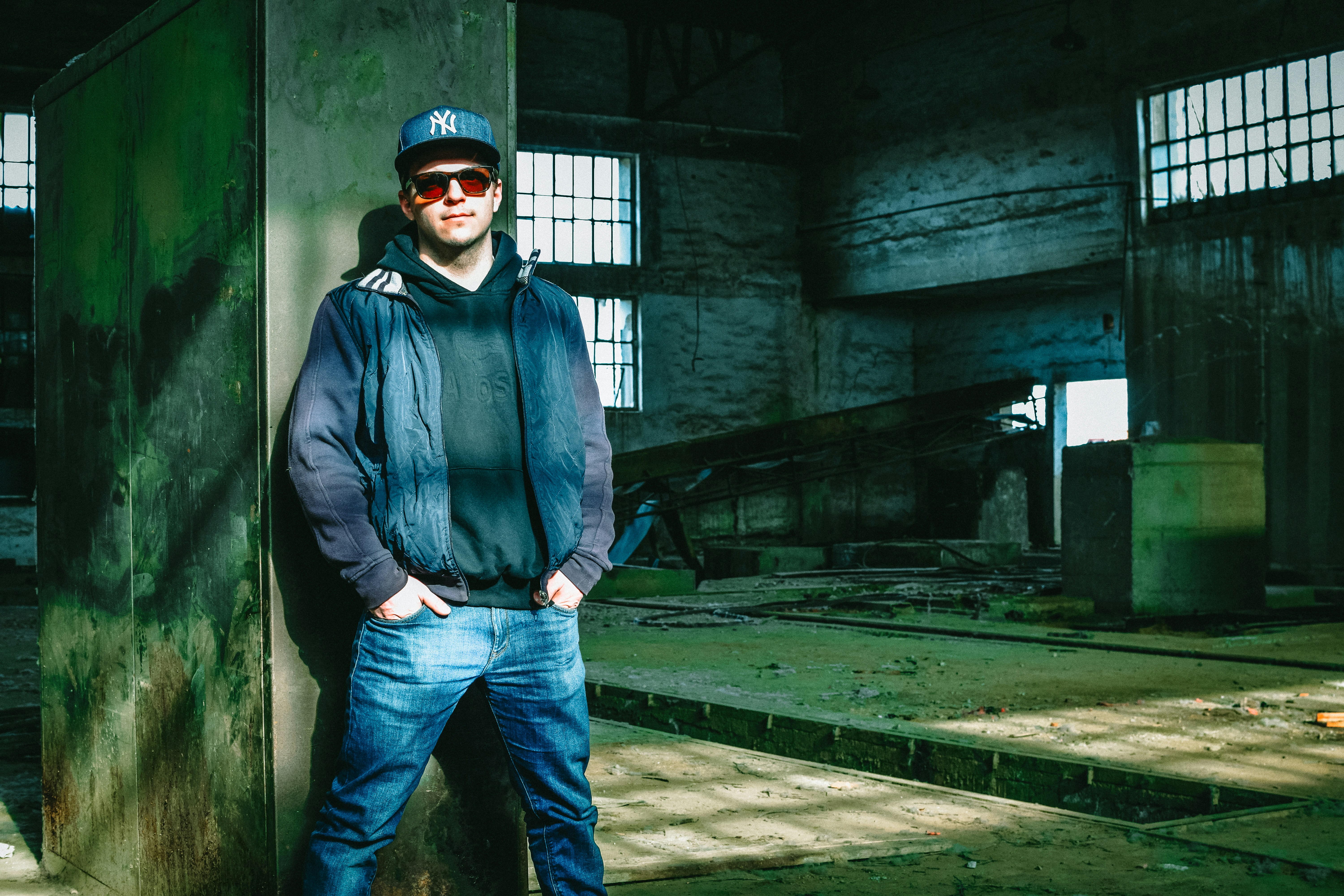 man in blue zip up jacket and blue denim jeans standing near gray concrete building during