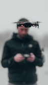 man in black hoodie wearing black and red r c drone