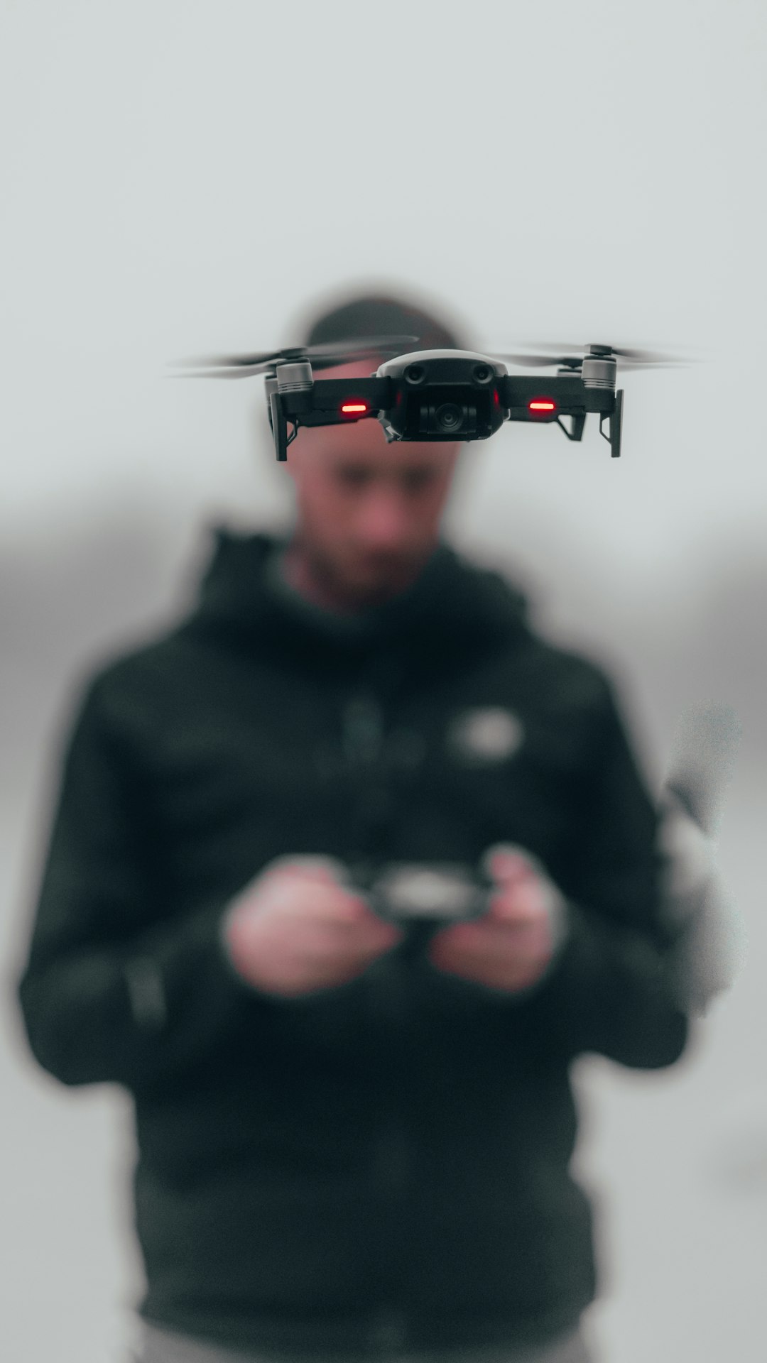 man in black hoodie wearing black and red r c drone