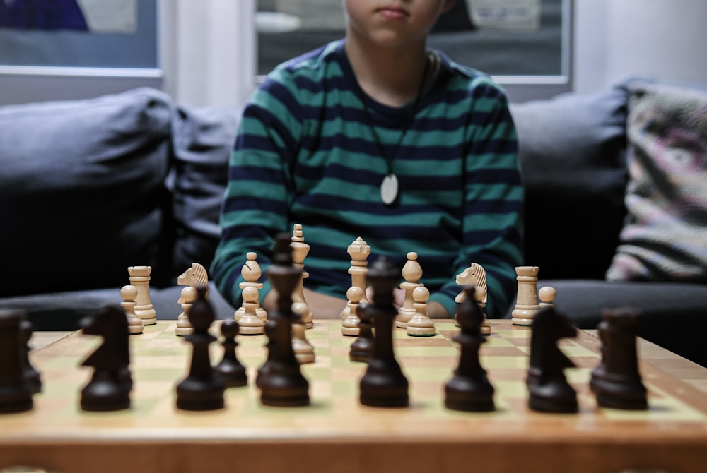 garçon en pull rayé vert et noir jouant aux échecs