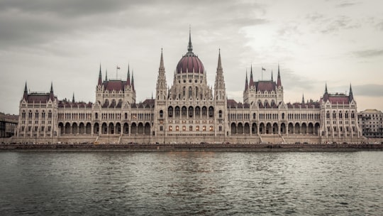 brown and white concrete building near body of water during daytime in Hungarian Parliament Building Hungary