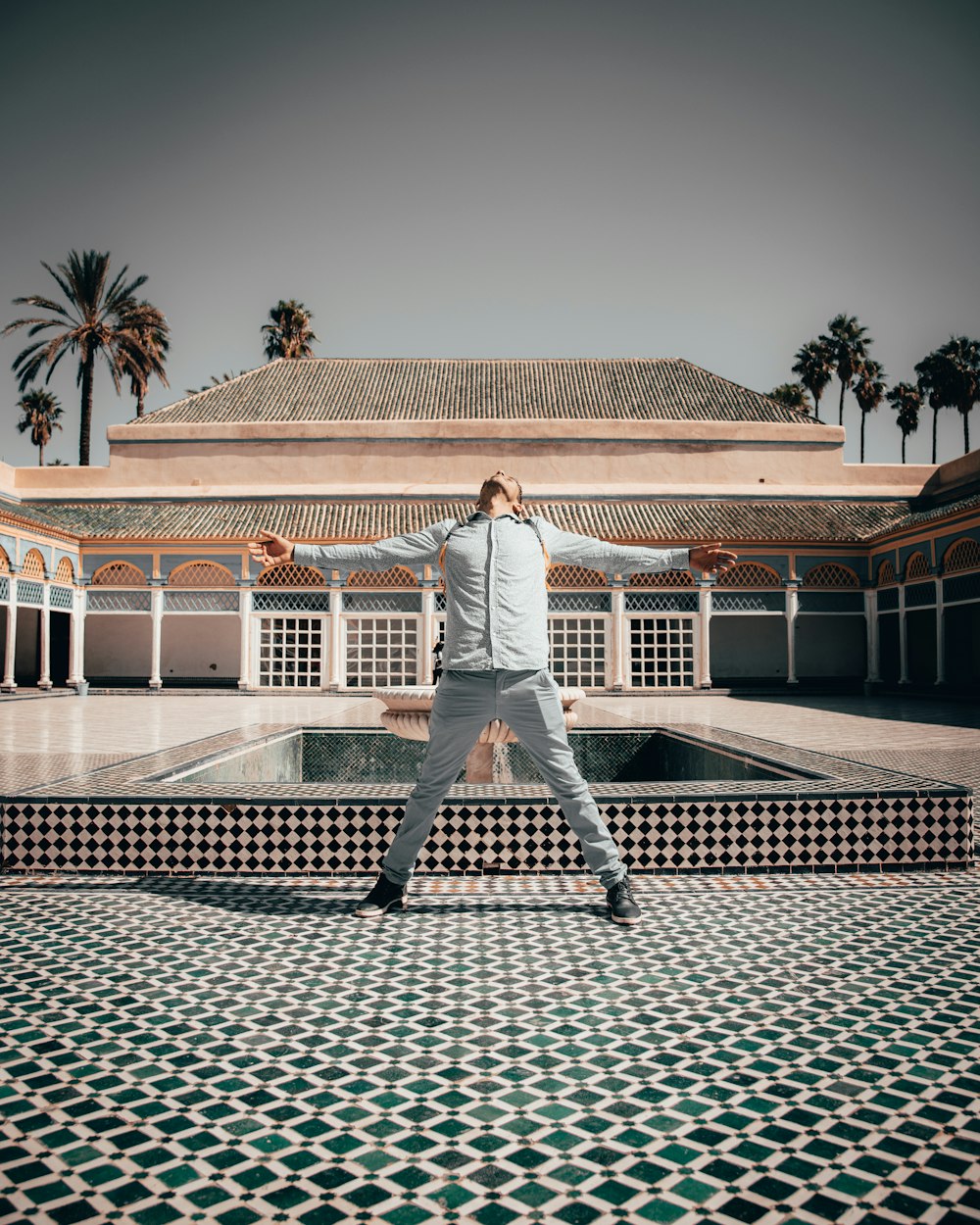 man in white shirt and gray pants walking on gray concrete pavement during daytime