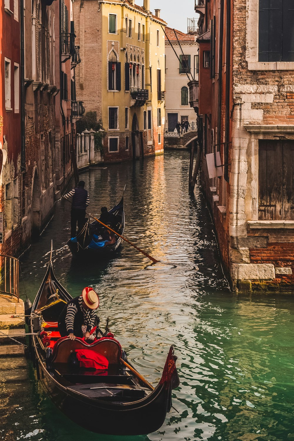 people riding on boat on river between concrete buildings during daytime