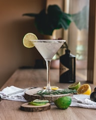 clear martini glass with sliced lemon on brown wooden table