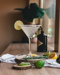 clear martini glass with sliced lemon on brown wooden table