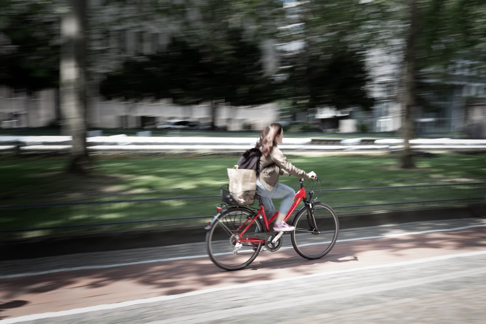 Mujer en chaqueta marrón montando en bicicleta en la carretera durante el día