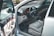 The focus is on the interior of a car with an open driver's side door, revealing a clean and well-maintained beige leather seat. The dashboard includes a steering wheel with a car logo, analog speedometer and gauges, and polished wood trim accents. Controls for windows and mirrors are visible on the door panel.