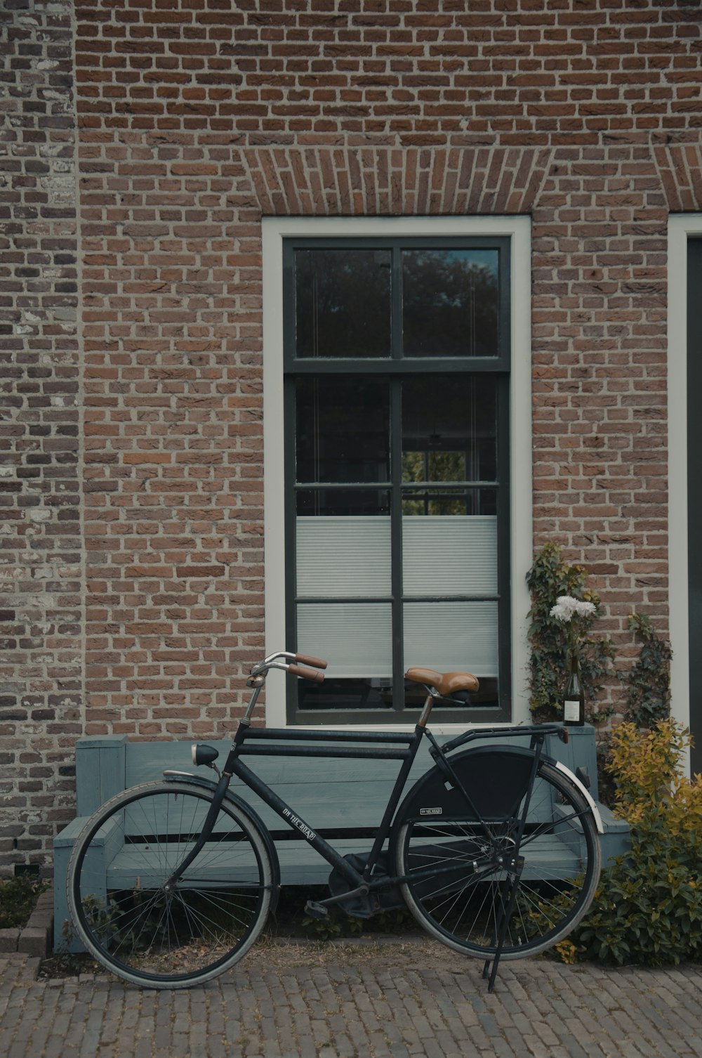 black bicycle beside brown brick wall