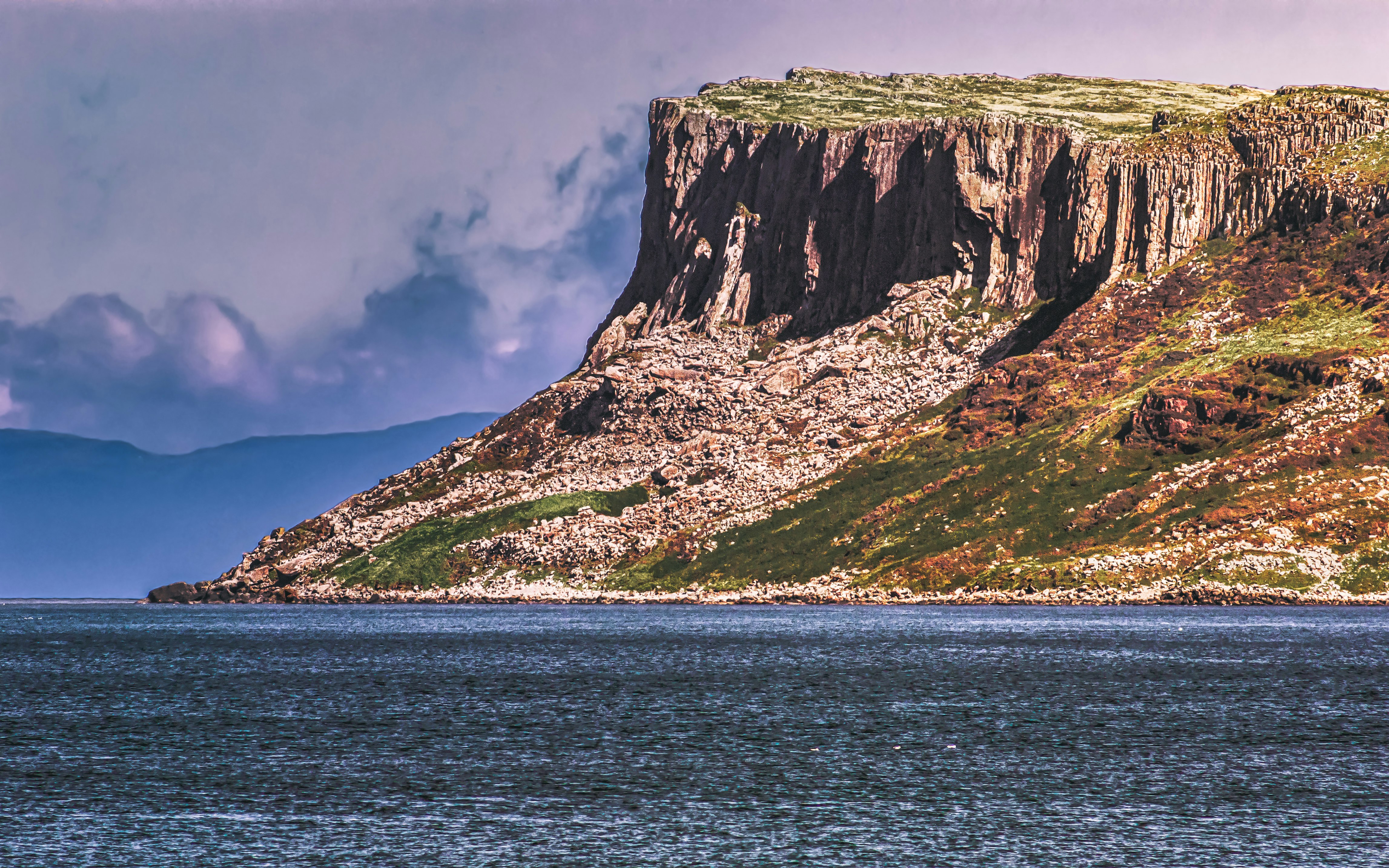 The mountain Fair Head's cliffs drop into the North Atlantic. The coast of Scotland is in the background. At this point, there is only 13 miles between Northern Ireland and Scotland (Aug, 2019).