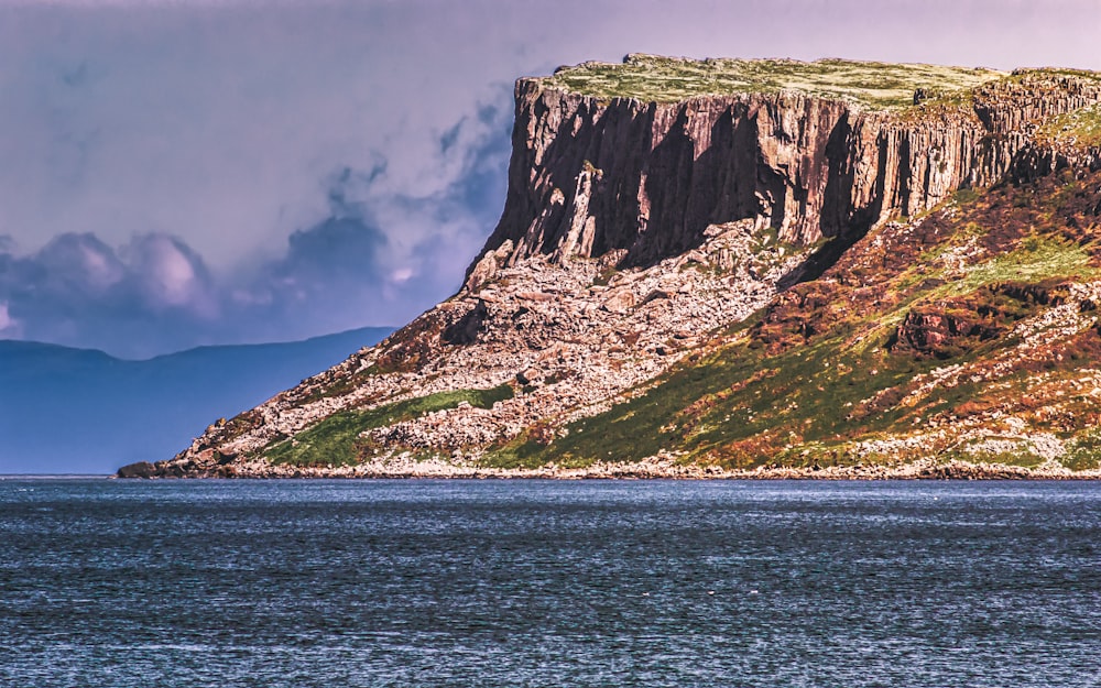 brown and green mountain beside body of water during daytime