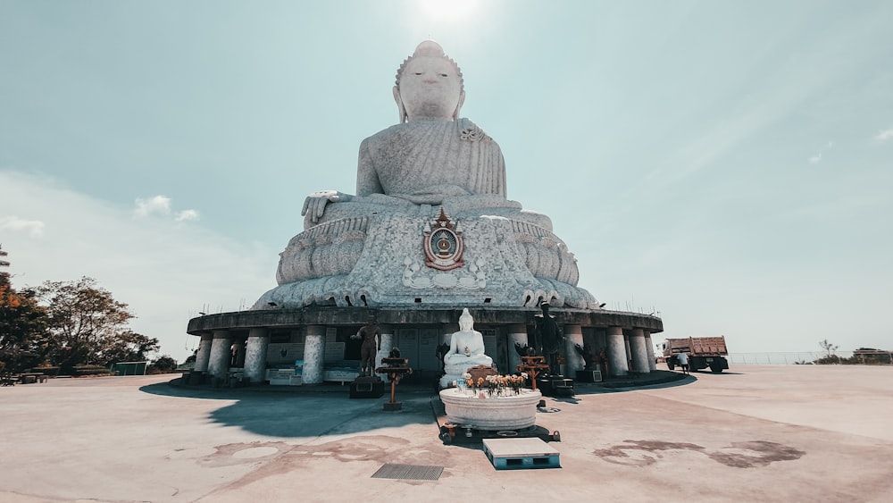 Statua di Buddha in cemento grigio sotto il cielo blu durante il giorno