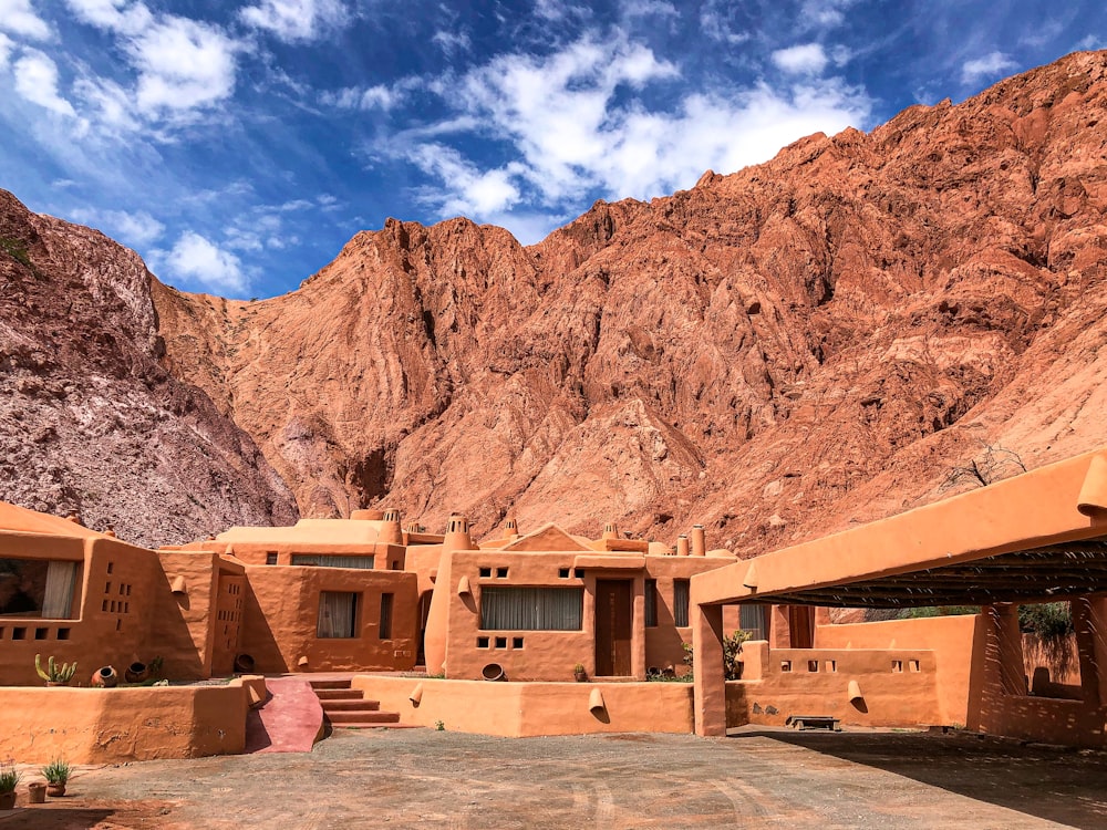 brown concrete building near brown rocky mountain under blue sky during daytime