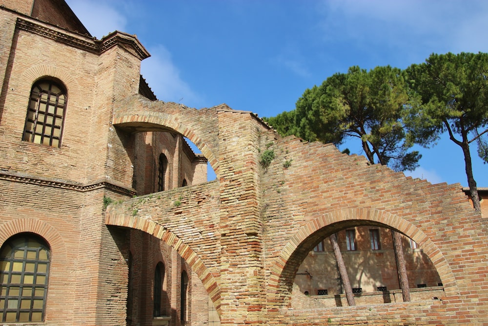 brown brick building near green trees under blue sky during daytime