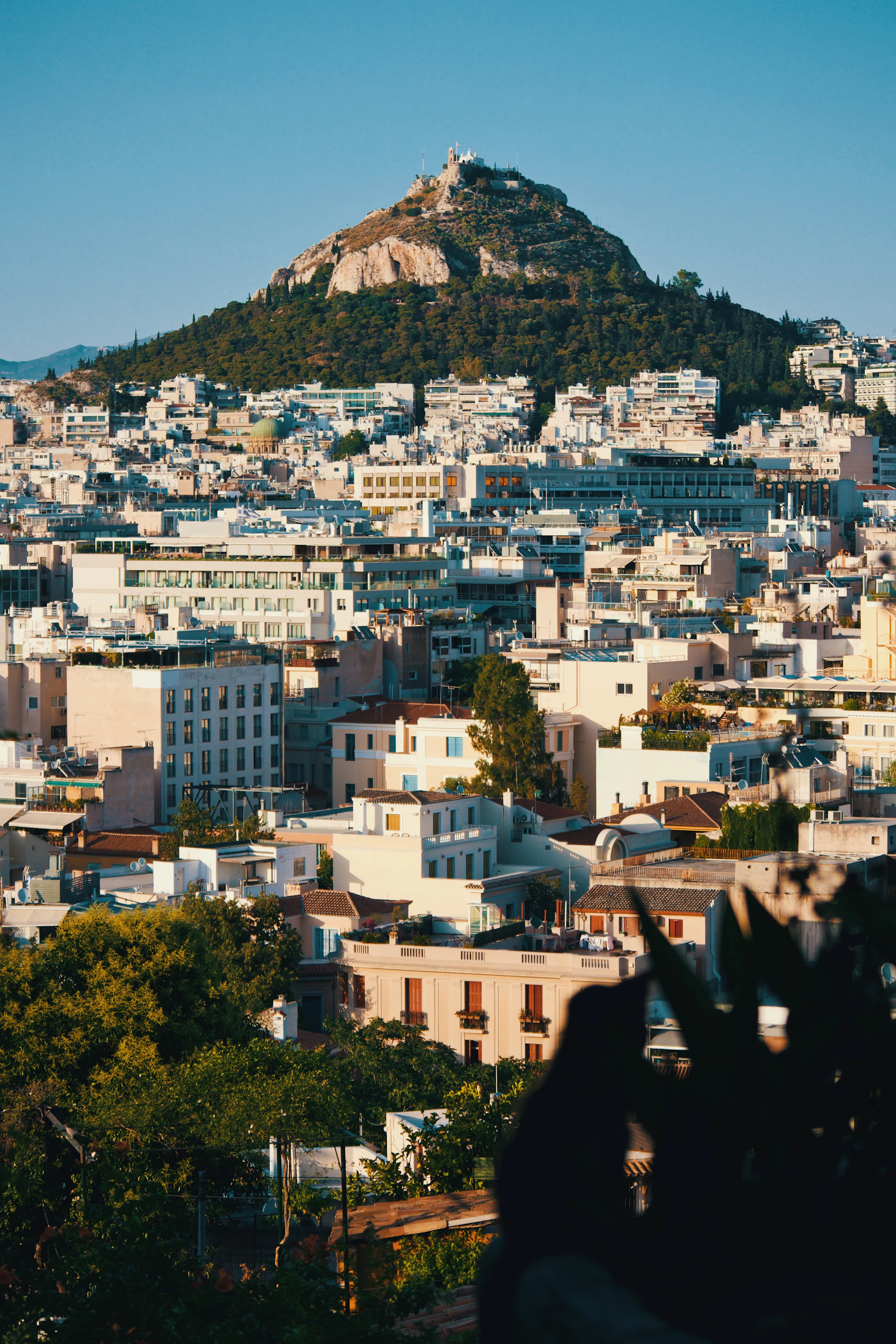 Lycabettus above the rooftops, the city climbing towards it.