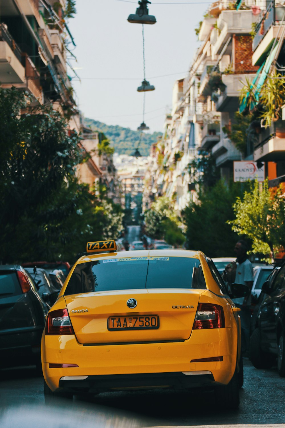 Ein gelbes Taxi fährt eine Straße neben hohen Gebäuden entlang