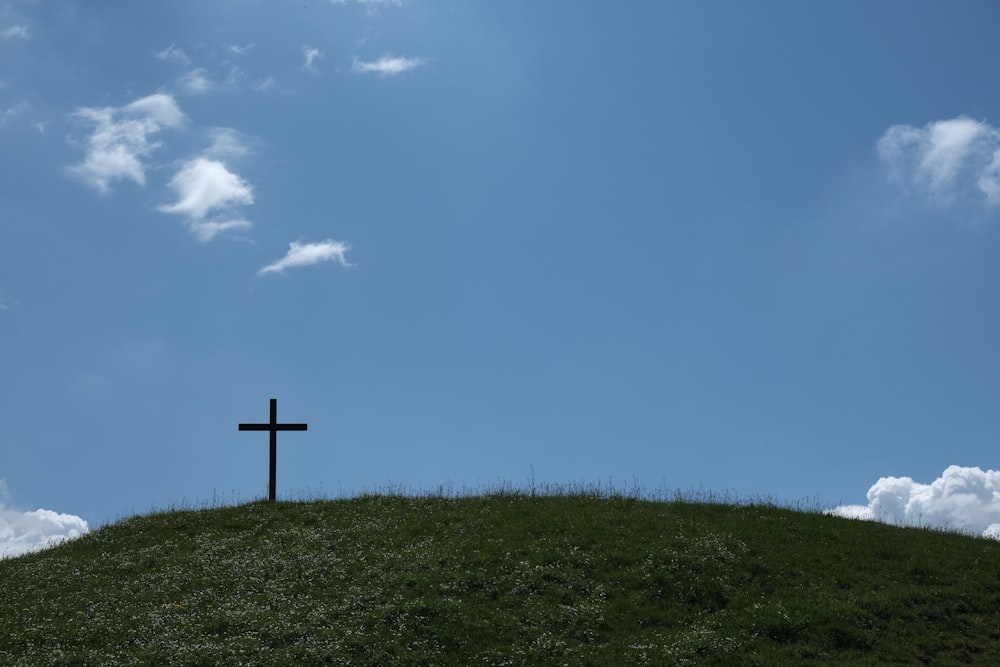 black cross on green grass under blue sky during daytime